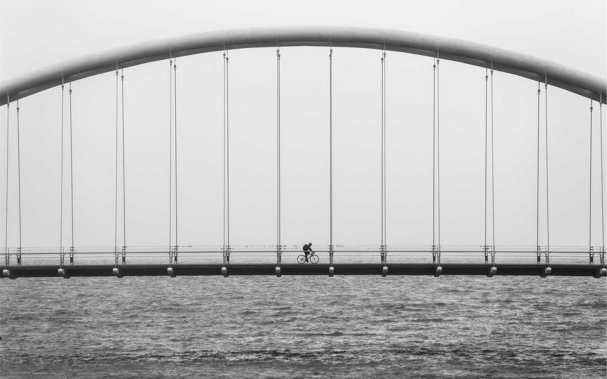 A steel arch bridge spanning still grey water